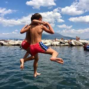 kinderen springen in de zee in napels